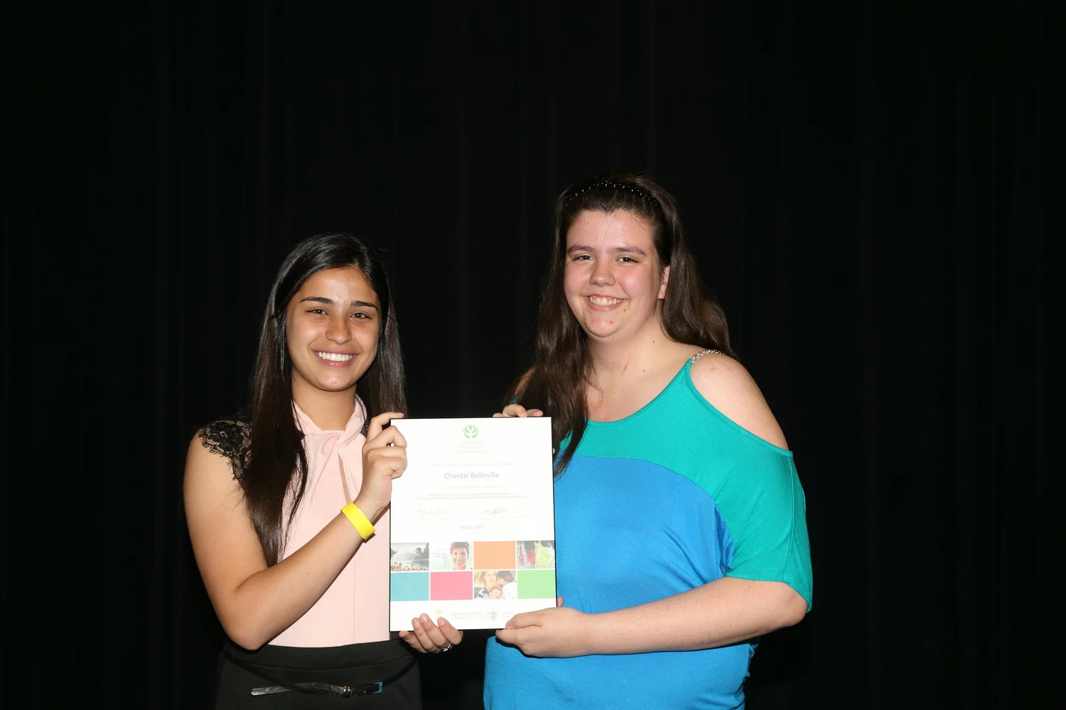 two teenagers holding an award certificate