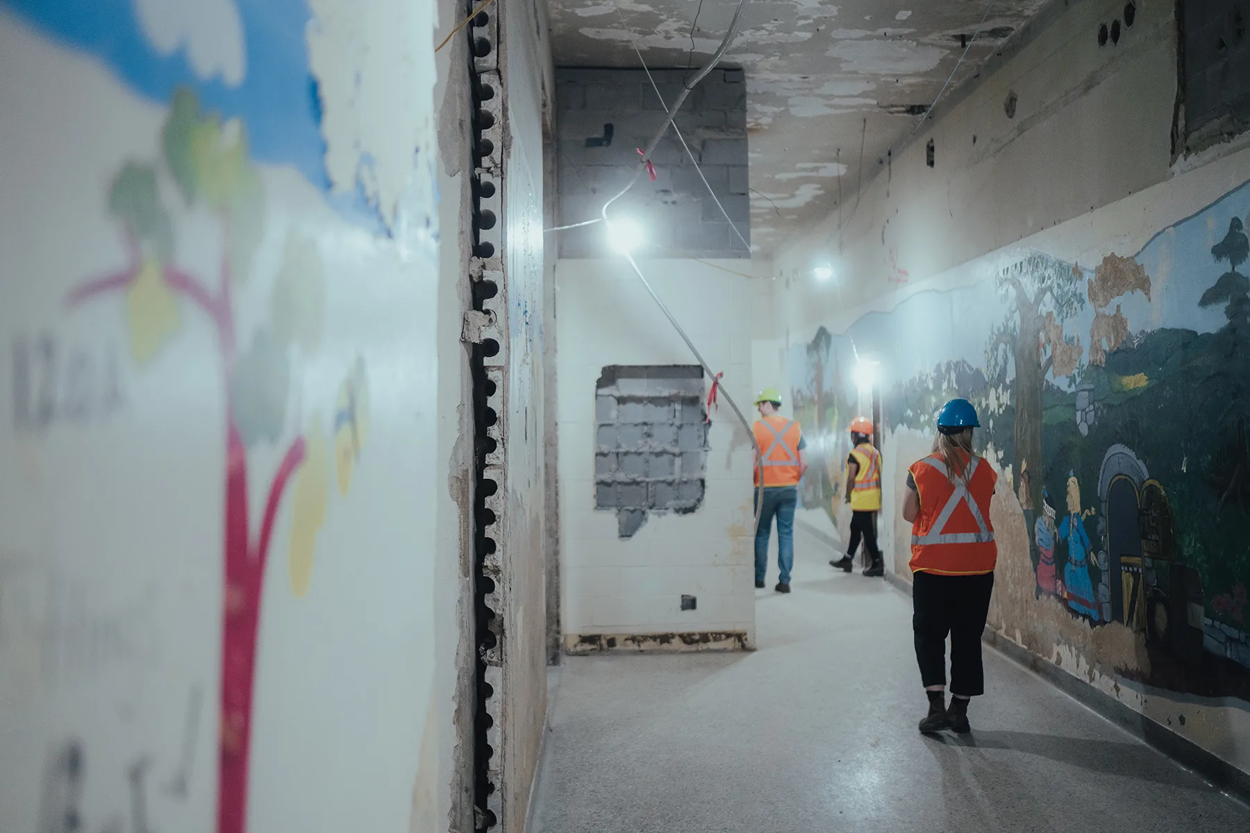 several workers in orange vests and hard hats working inside a building