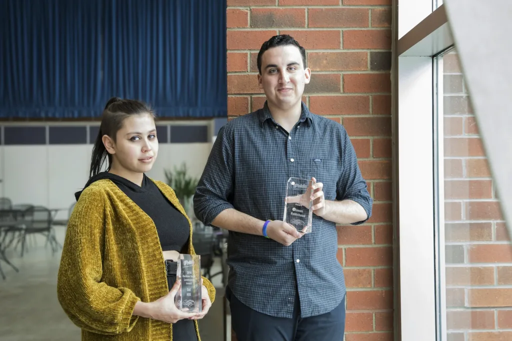 Two students holding their awards