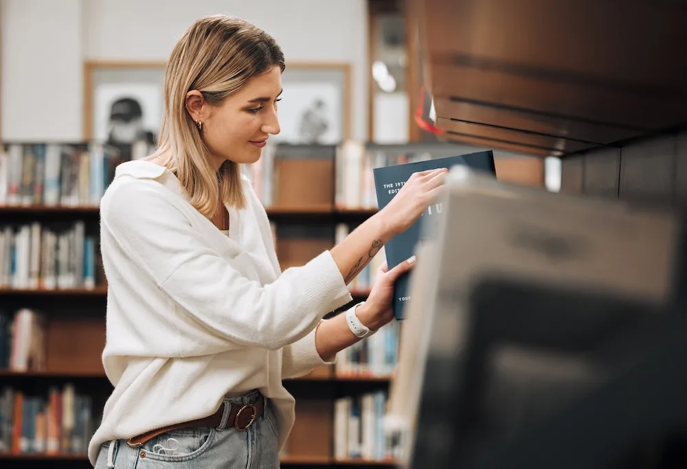 A woman examining books on a bookshelf