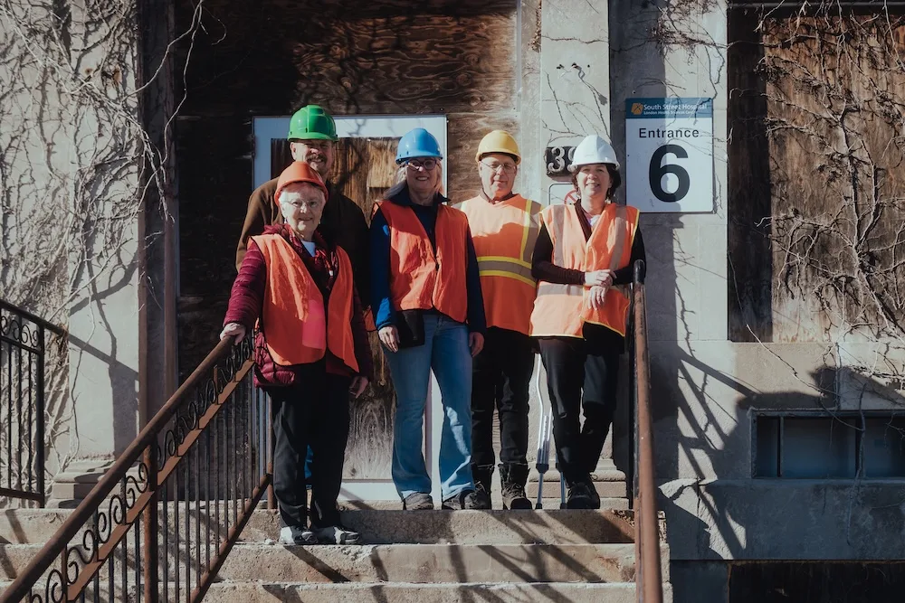 A group of people wearing orange vests and hard hats.