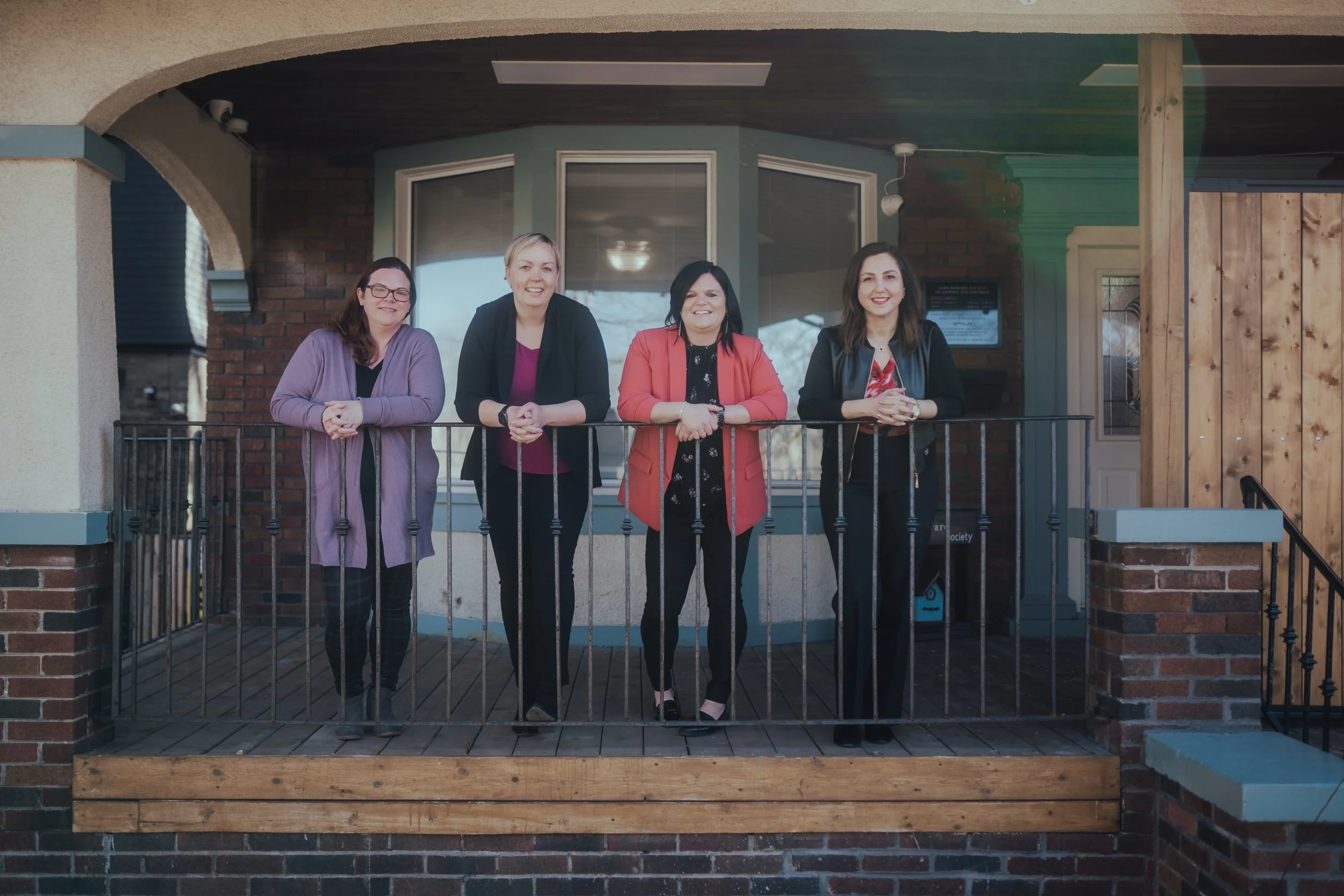 four people stand on a porch