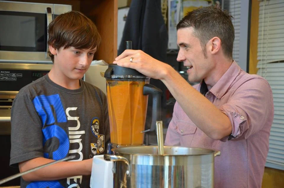man showing a teenager how to use a blender