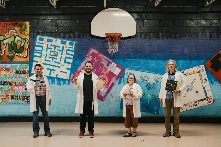 Four adults on a basketball court wearing white labcoats